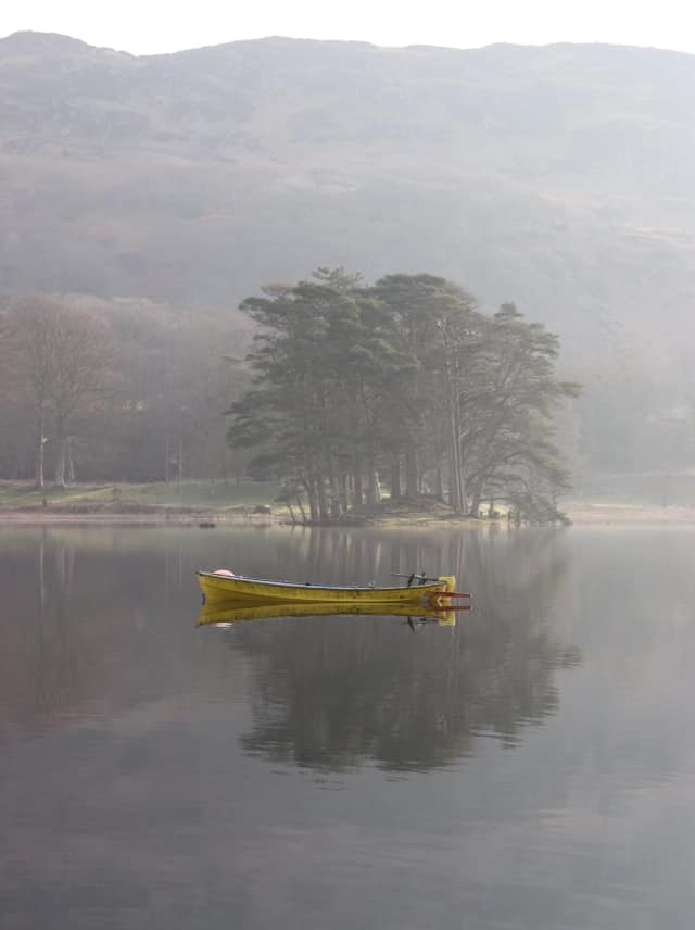 Small boat reflection on water in the Lake District